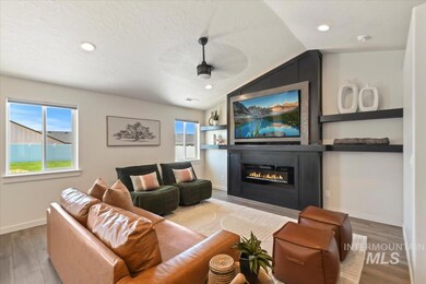 Living room featuring lofted ceiling, a glass covered fireplace, wood finished floors, recessed lighting, and a textured ceiling