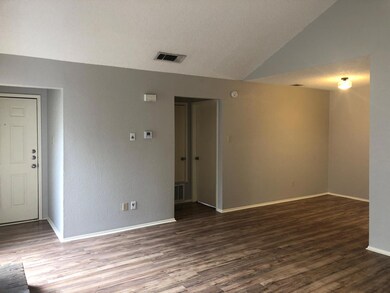 Spare room with dark wood-style flooring, a textured ceiling, lofted ceiling, and a textured wall