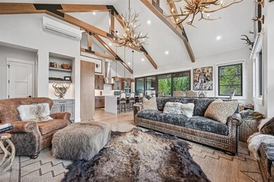 Living area featuring a chandelier, beamed ceiling, high vaulted ceiling, wood finished floors, and a wall mounted air conditioner