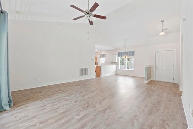 Unfurnished living room featuring high vaulted ceiling, a ceiling fan, light wood-style floors, baseboards, and a chandelier