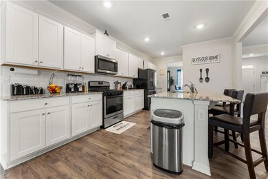 Kitchen featuring a kitchen island with sink, dark