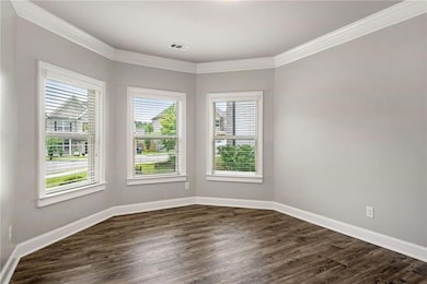 Spare room with ornamental molding, dark wood finished floors, and baseboards