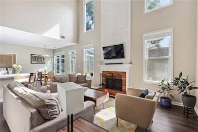 Living room with a brick fireplace, a towering ceiling, and dark wood-type flooring