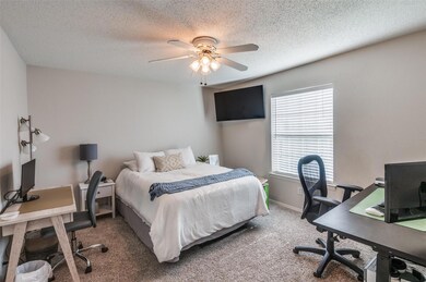 Bedroom with a textured ceiling, multiple windows,