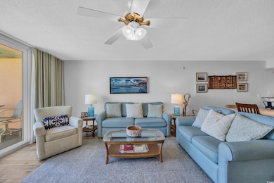 Living area featuring light wood finished floors, a textured ceiling, and ceiling fan