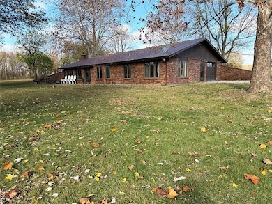 Rear view of house with brick siding, a lawn, a chimney, and a garage