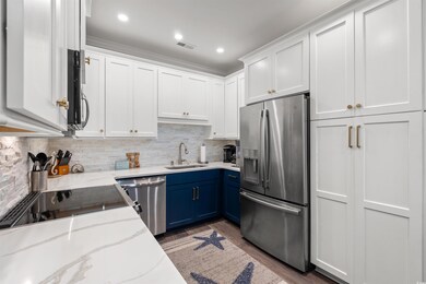 Kitchen featuring white cabinets, a sink, stainless steel appliances, and blue cabinets