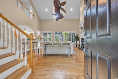 Foyer with high vaulted ceiling, ceiling fan, stairs, light wood-style floors, and a fireplace