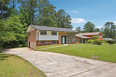 Split foyer home featuring driveway, a garage, brick siding, and a front lawn