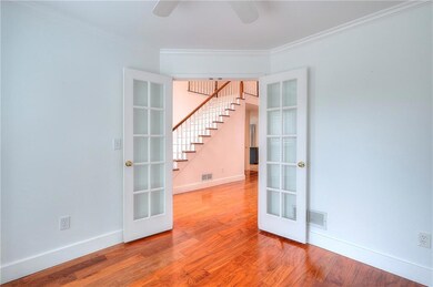 Office/bonus room with French doors, stairs, a ceiling fan, crown molding, and wood finished floors.