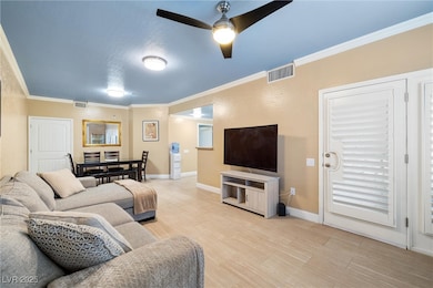 Living area with crown molding, ceiling fan, baseb