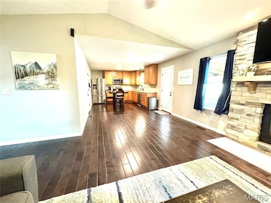 Unfurnished living room with vaulted ceiling, dark wood finished floors, a stone fireplace, and recessed lighting