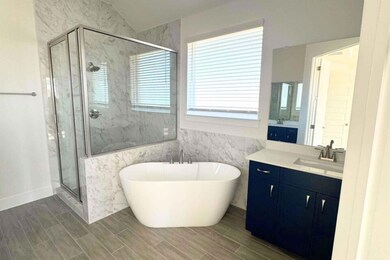 Bathroom featuring vanity, a marble finish shower, a soaking tub, tile walls, and wood finish floors