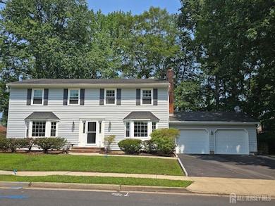 colonial inspired home with a chimney, a garage, driveway, and a front lawn