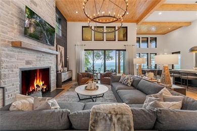 Living room with 15ft wooden ceiling with exposed beams, wood finished floors, a chandelier, a high ceiling, and healthy amount of natural light