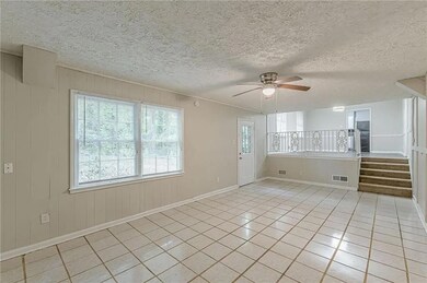 Unfurnished room featuring light tile patterned floors, a textured ceiling, ceiling fan, stairs, and wooden walls