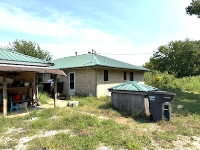 Rear view of property with a metal roof and brick siding