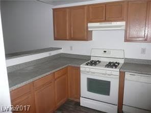 Kitchen with white appliances, dark countertops, b