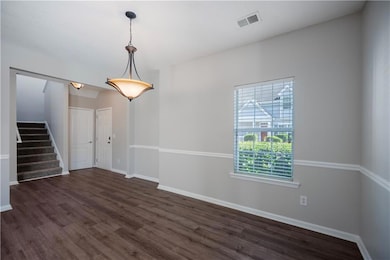 Spare room with stairs, dark wood-style floors, and baseboards