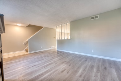 Empty room featuring a textured ceiling, wood finished floors, stairway, and baseboards