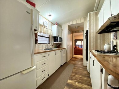 Kitchen featuring white appliances, white cabinetry, dark wood-type flooring, and sink