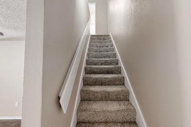 Staircase featuring baseboards and a textured ceil