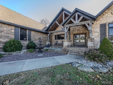Doorway to property with stone siding, a porch, and roof with shingles