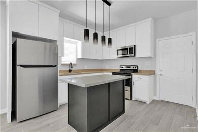 Kitchen featuring stainless steel appliances, a sink, white cabinetry, and wood tiled floors