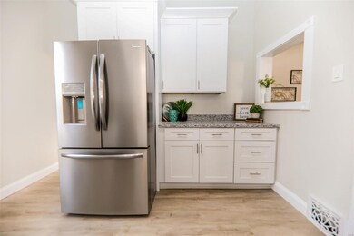 Kitchen with white cabinets, stainless steel fridge with ice dispenser, and light hardwood / wood-style flooring