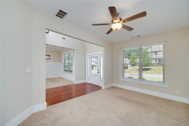Carpeted spare room with healthy amount of natural light, ceiling fan, and wood finished floors
