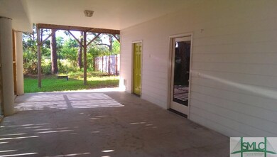 Drive under carport shows glass entry door and the