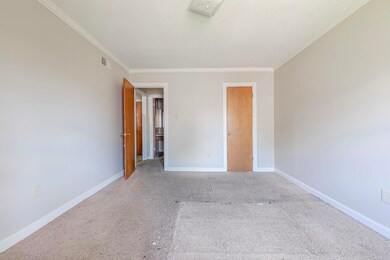 Unfurnished bedroom with ornamental molding and carpet flooring