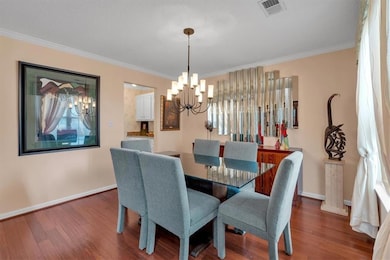 Dining area featuring a chandelier, crown molding, wood finished floors, and baseboards