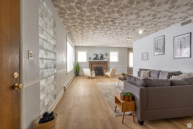 Living room with visible vents, wood finished floors, a fireplace, and a baseboard radiator
