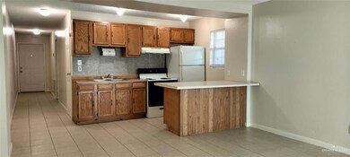 Kitchen featuring under cabinet range hood, a sink, electric range oven, freestanding refrigerator, and brown cabinetry