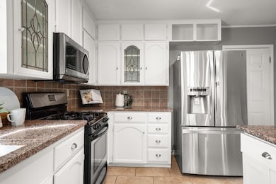 Kitchen featuring white cabinets, stainless steel