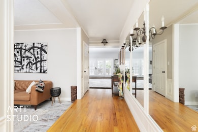 Corridor featuring french doors, wood finished floors, ornamental molding, and a chandelier