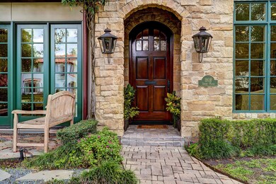 Front entry with stone facade flanked by classic gas fixtures and casement windows with views of the park.
