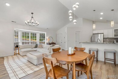 Dining space with light wood-style flooring, high vaulted ceiling, recessed lighting, and a chandelier