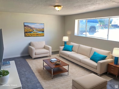 Carpeted living room with a textured ceiling and baseboards