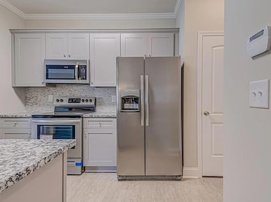 Kitchen with light stone counters, crown molding, 
