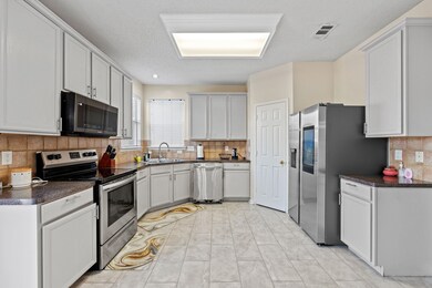 Kitchen with dark countertops, appliances with stainless steel finishes, tasteful backsplash, a textured ceiling, and white cabinetry