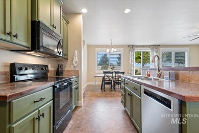 Kitchen featuring green cabinetry, black appliances, dark countertops, recessed lighting, and decorative light fixtures