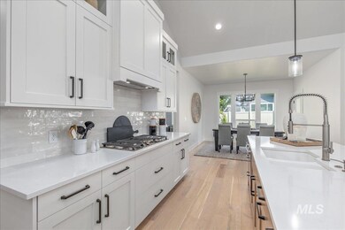 Kitchen featuring stainless steel gas stovetop, light wood-style flooring, backsplash, white cabinets, and recessed lighting