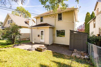Rear view of property featuring a lawn, a storage 