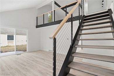 Stairway with high vaulted ceiling and wood finished floors