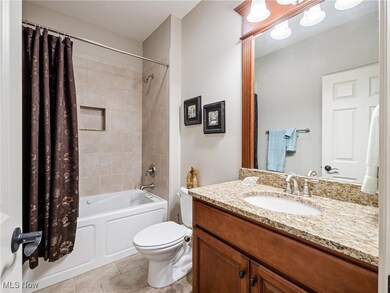 Bathroom featuring shower / bathtub combination with curtain, vanity, and light tile patterned floors