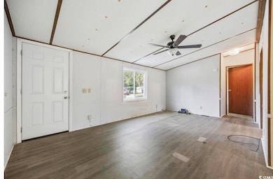 Unfurnished living room with wood finished floors, ceiling fan, and vaulted ceiling