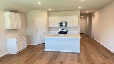 Kitchen with light countertops, stainless steel appliances, an island with sink, white cabinetry, and recessed lighting