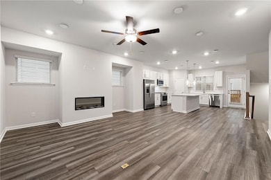Unfurnished living room with sink, dark hardwood / wood-style floors, and ceiling fan